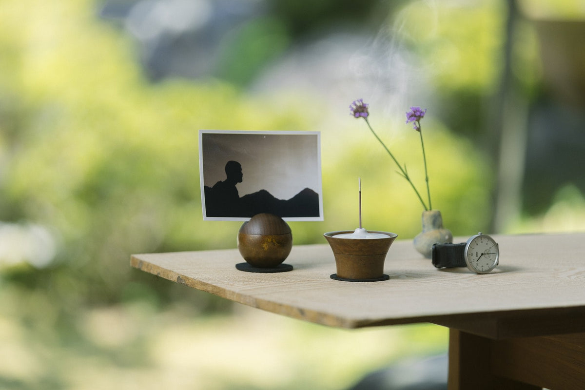 窓辺のテーブルに、写真とおりん、花を並べた手元供養の場