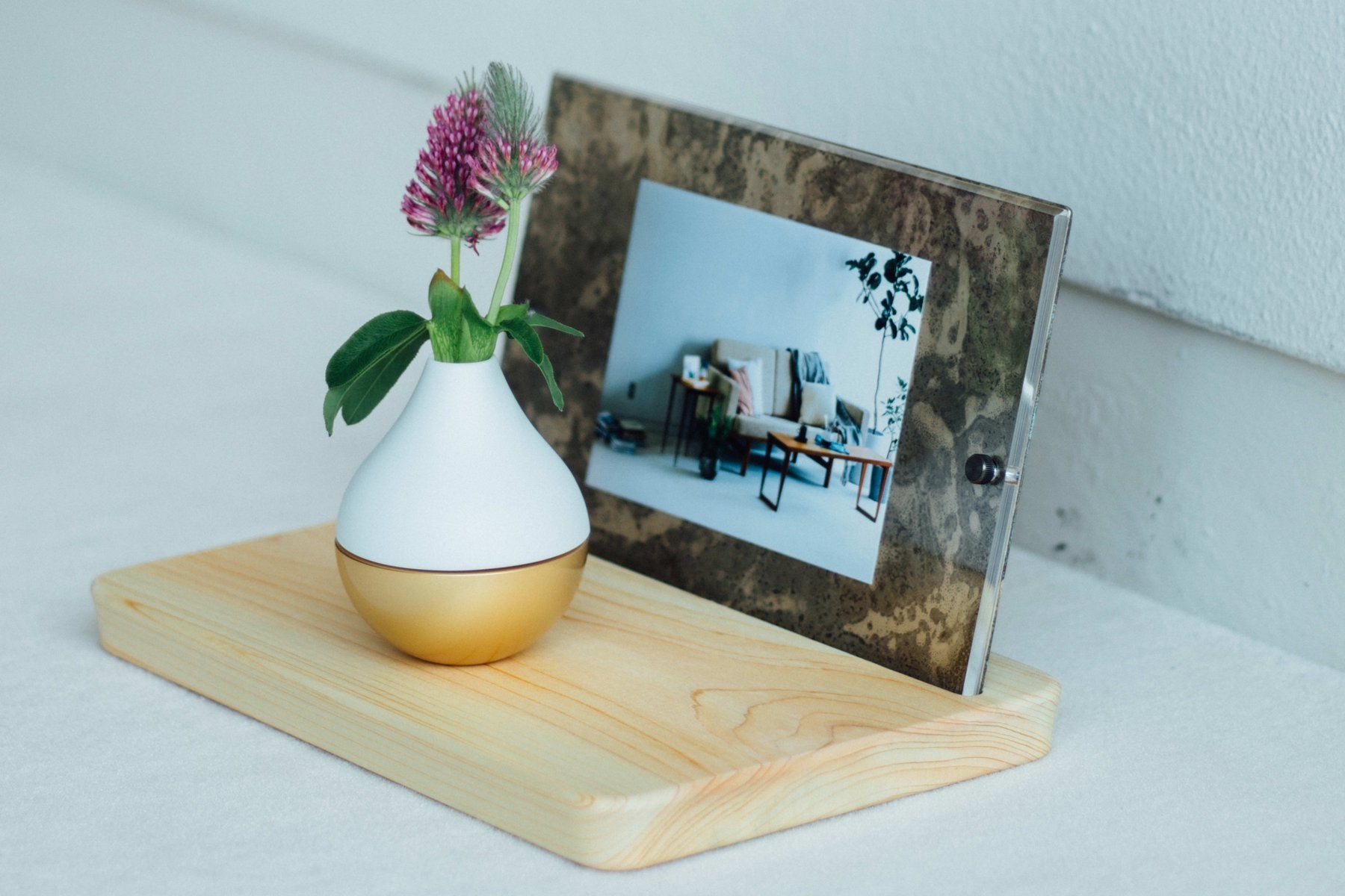 木製台座に、大理石調フレームでリビングの写真を挟んだPicstalと、白磁の花瓶を並べた生活シーン